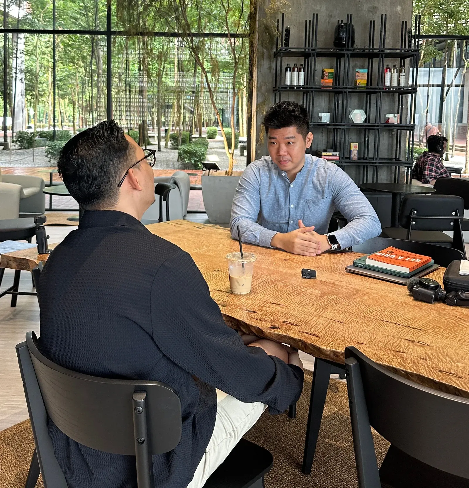 Adrian Ching in conversation across a table at a café